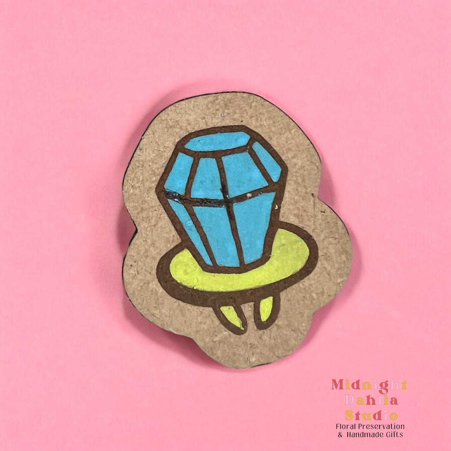 A wooden pin with a hand painted ring pop candy with blue candy and a lime green base