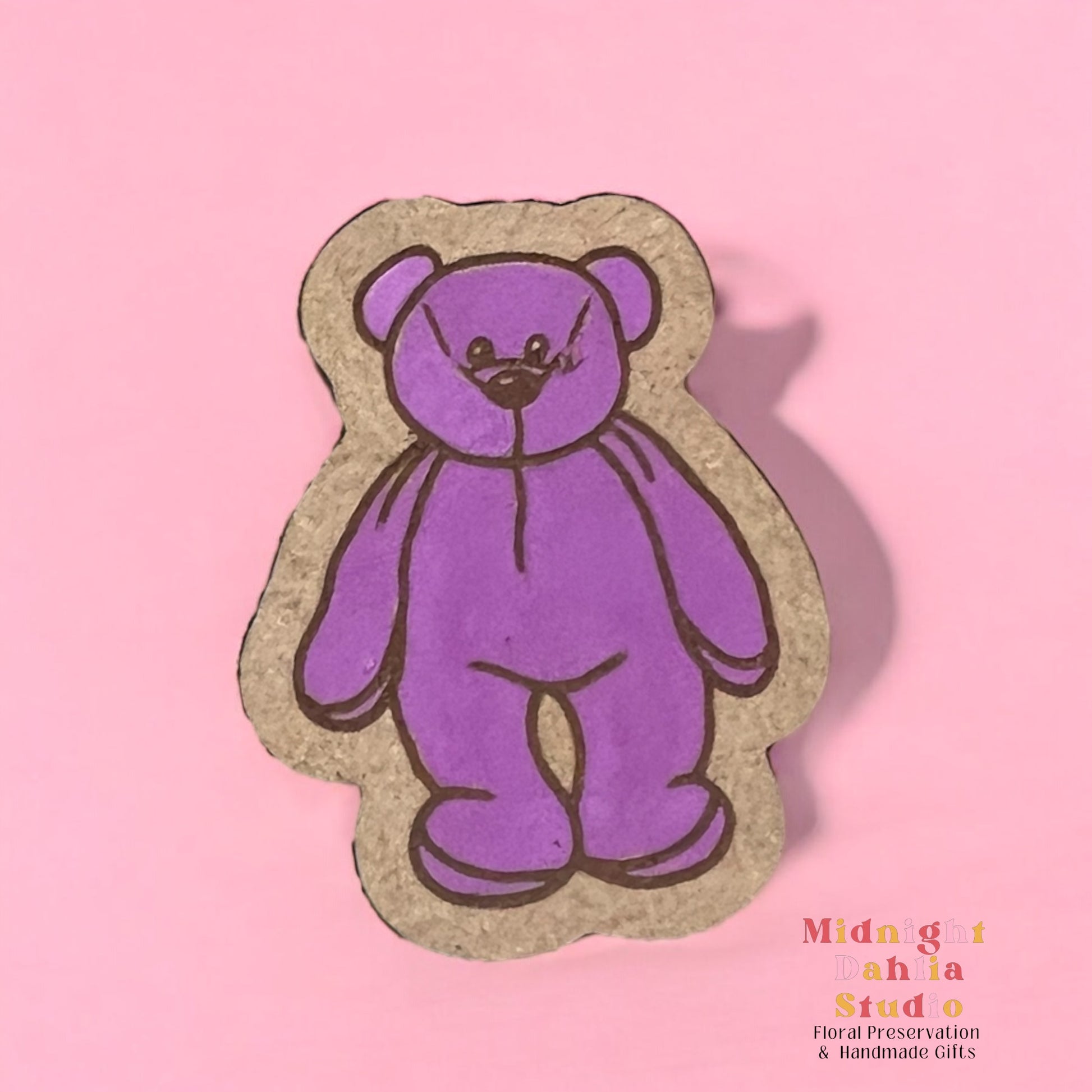 A wooden pin with a hand painted purple beanie baby bear