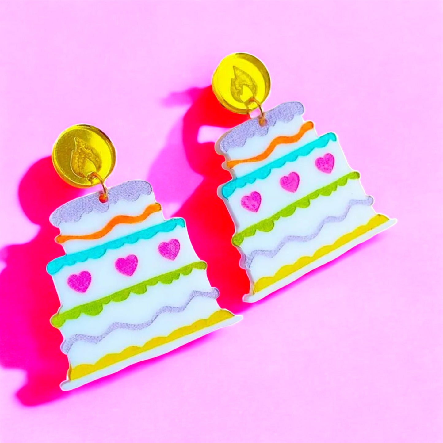 colorful tiered birthday cake shaped dangle earrings with handpainted frosting and hearts hanging from a gold base with an etched flame.  perfect birthday gift jewelry woman women.