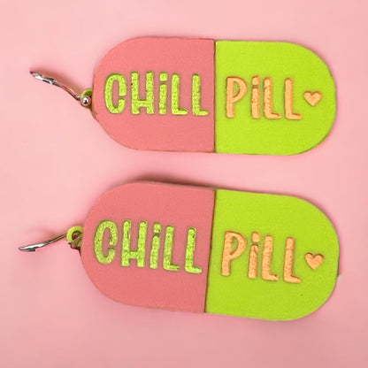 a pair of oval earrings with light pink and lime green, that reads chill pill with a little heart.  a perfect gift for mom, women, and teens.