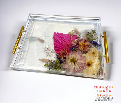 A custom acrylic tray filled with bright flowers including a peony and roses and crystal clear resin.  A beautiful way to preserve a bridal bouquet.