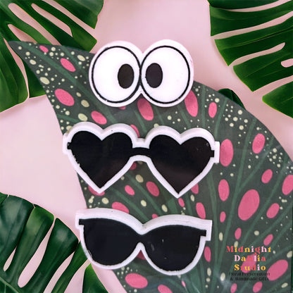 a set of three plant personality magnets including a cross eyed pair of eyes, heart shaped sunglasses, and wayfarer sunglasses