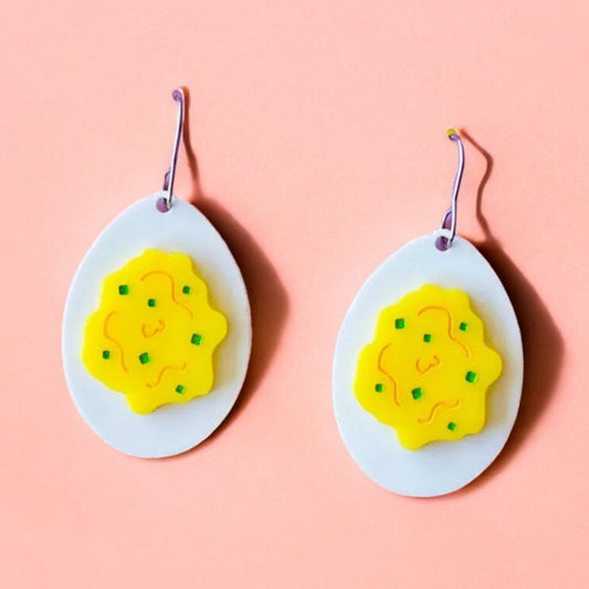 A pair of earrings shaped like eggs with a white acrylic background and yellow on top to make it look like a deviled egg.  Perfect easter accessory.