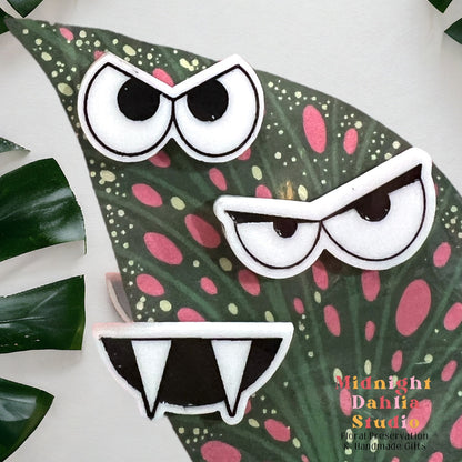 a set of three plant personality magnets in two kinds of evil eyes and a vampire tooth smile