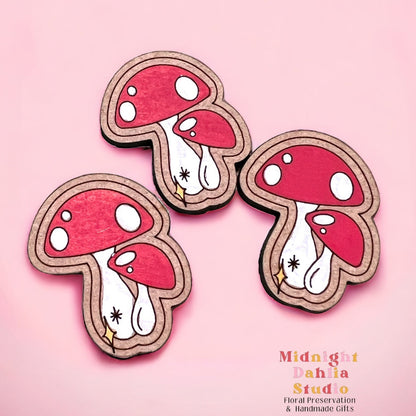 a set of three mushroom shaped magnets with red and white mushrooms and a small yellow star at the bottom