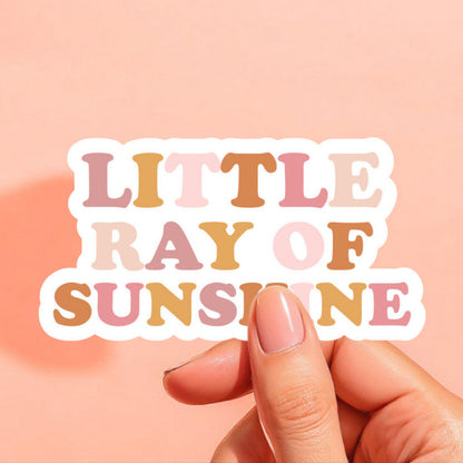 a white background sticker that reads little ray of sunshine in pinks and yellows