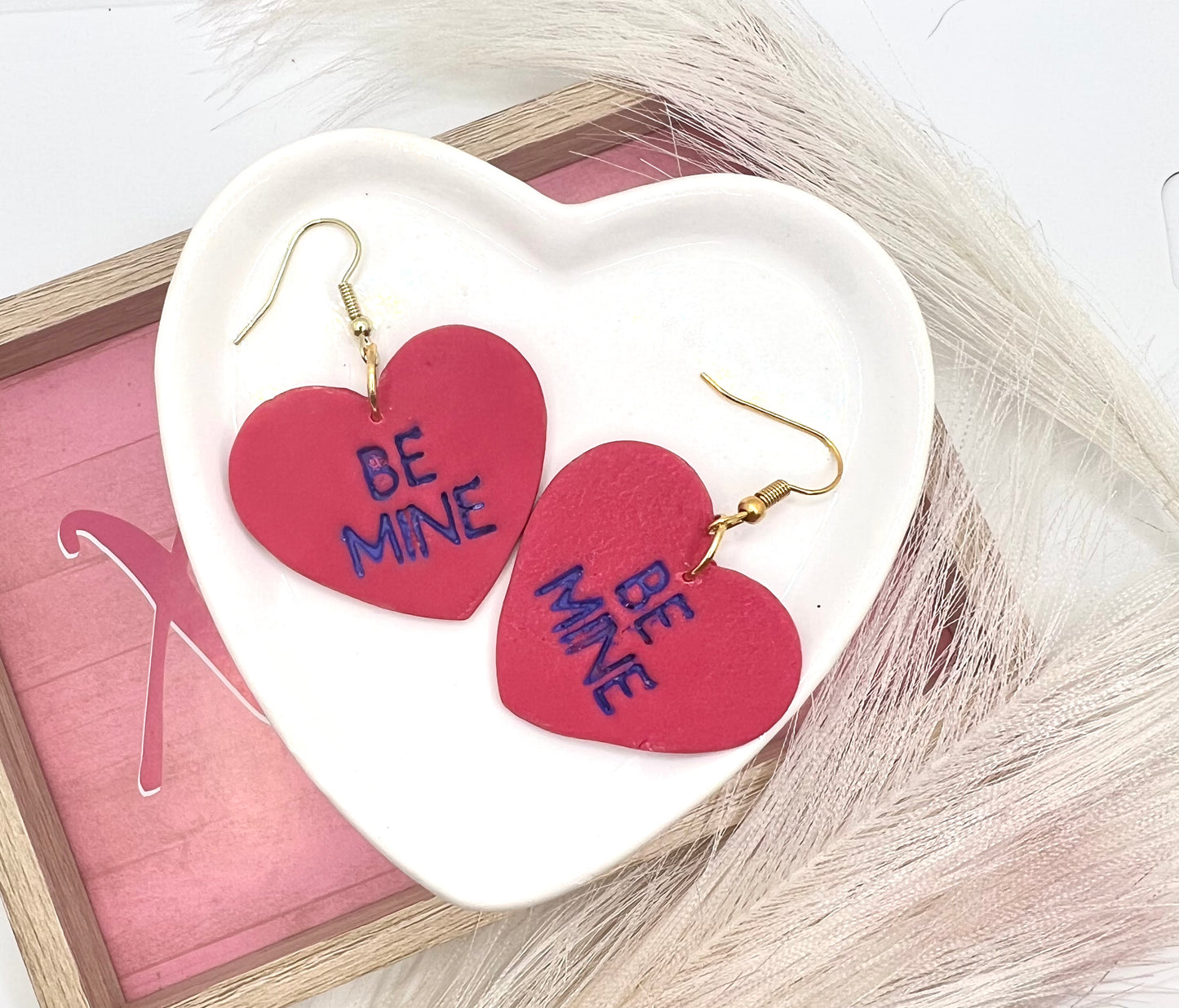 heart shaped earrings stamped with be mine in purple and on gold fish hook style earrings.