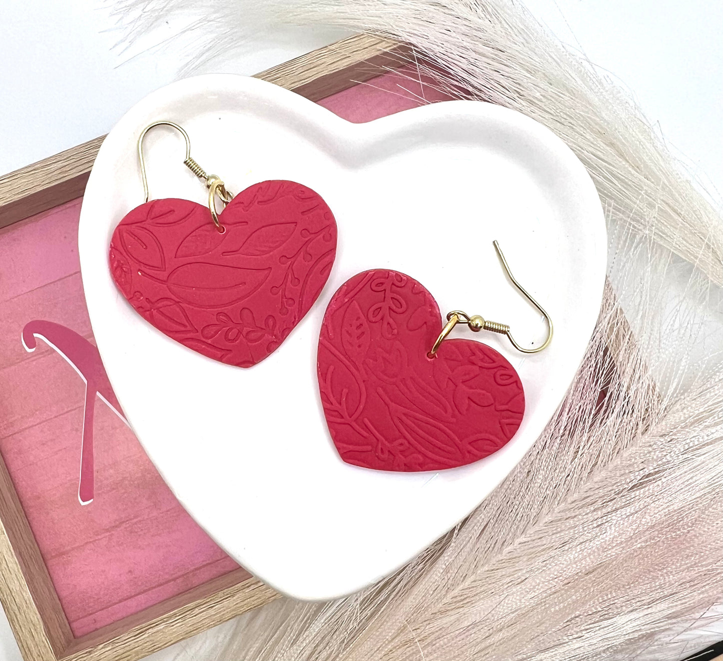 heart shaped earrings embossed with a floral pattern.  they are on gold fish hook style earrings.
